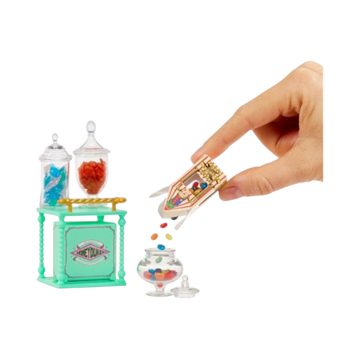Main de personne versant des bonbons miniatures dans un bocal du playset Miniverse Honeydukes de La boutique Aux 2 Balais