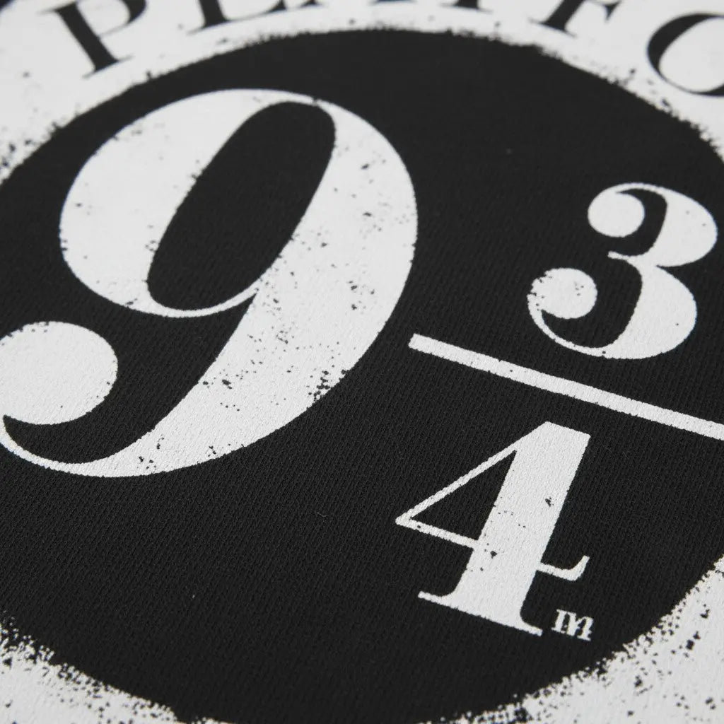 La boutique Aux 2 Balais T-shirt noir en polyester avec le logo Platform 9 3/4 effet vieilli blanc, col rond, coupe standard.