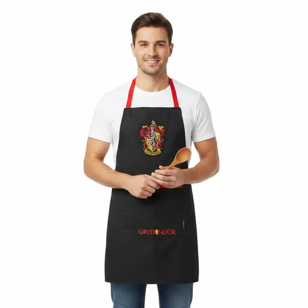 Tablier noir La boutique Aux 2 Balais Gryffondor Harry Potter en polyester et coton avec écusson et inscription.