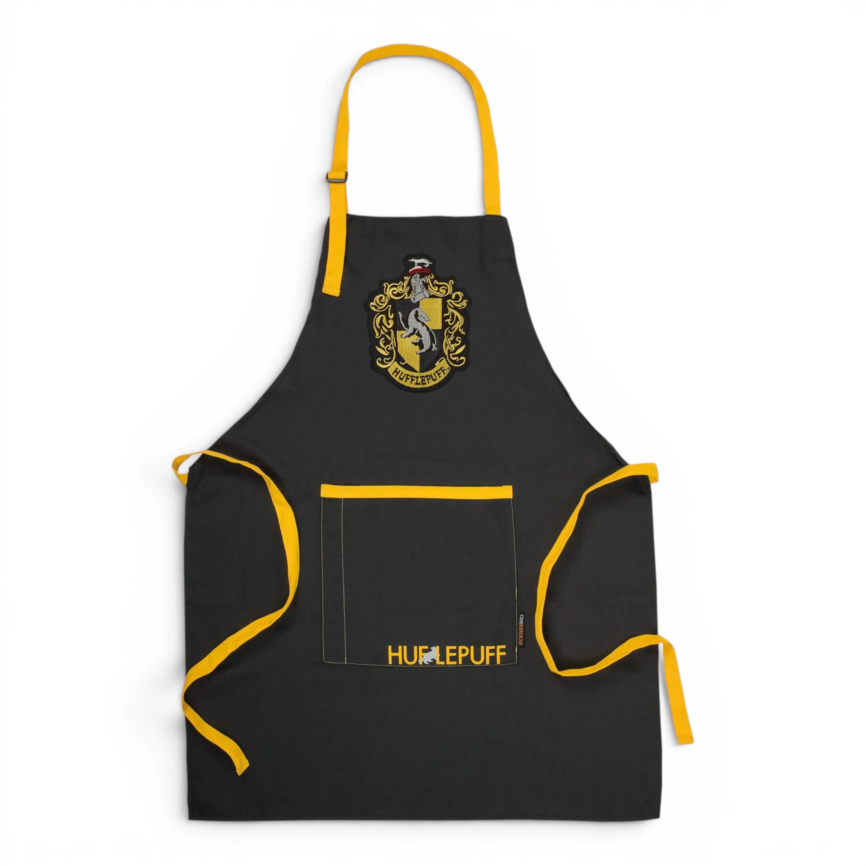 Tablier noir unisexe La boutique Aux 2 Balais Harry Potter Poufsouffle avec écusson, inscription Hufflepuff et poche frontale. 80% polyester, 20% coton.