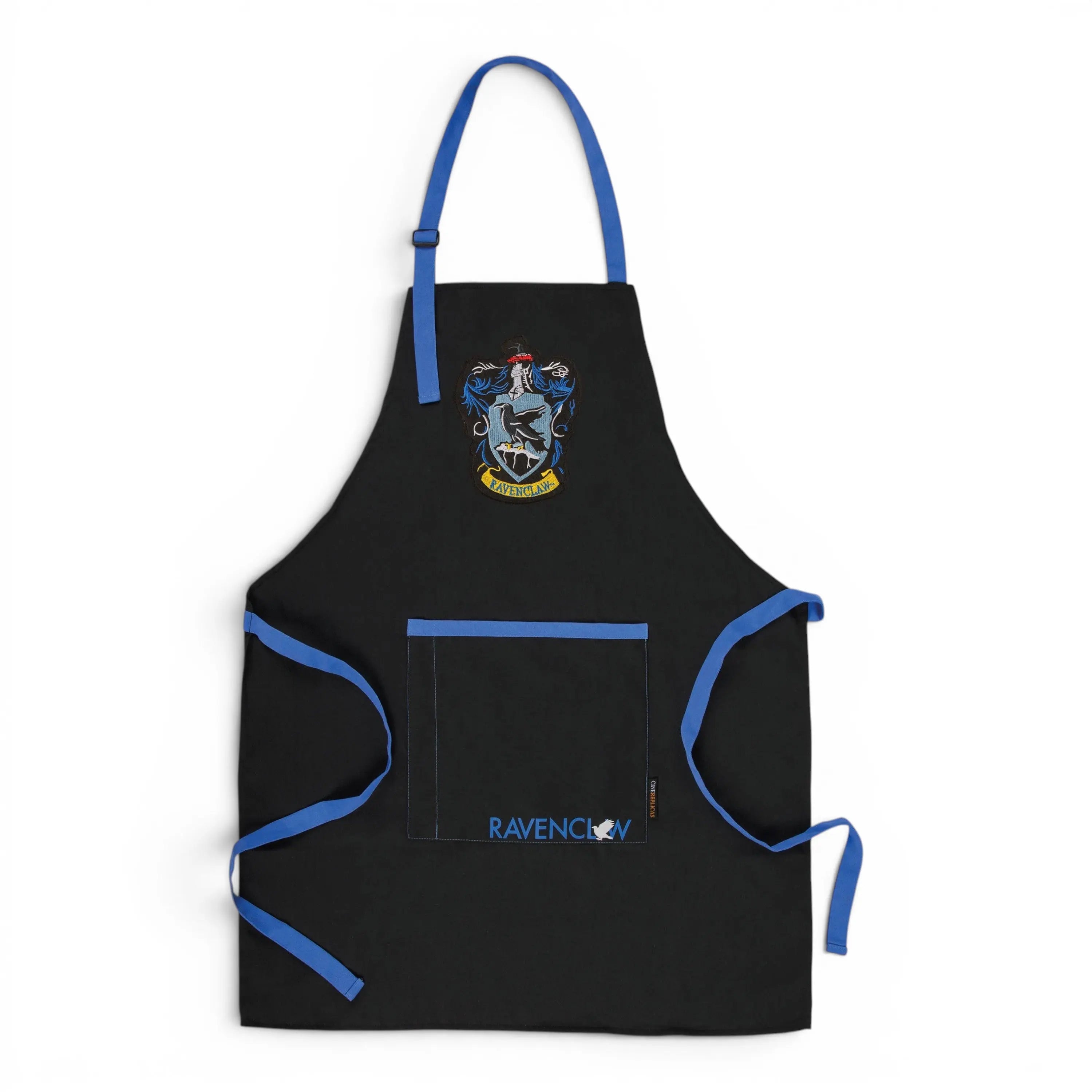 La boutique Aux 2 Balais Tablier Serdaigle noir avec blason et inscription Ravenclaw, bordures bleues, poche frontale. Polyester/coton.