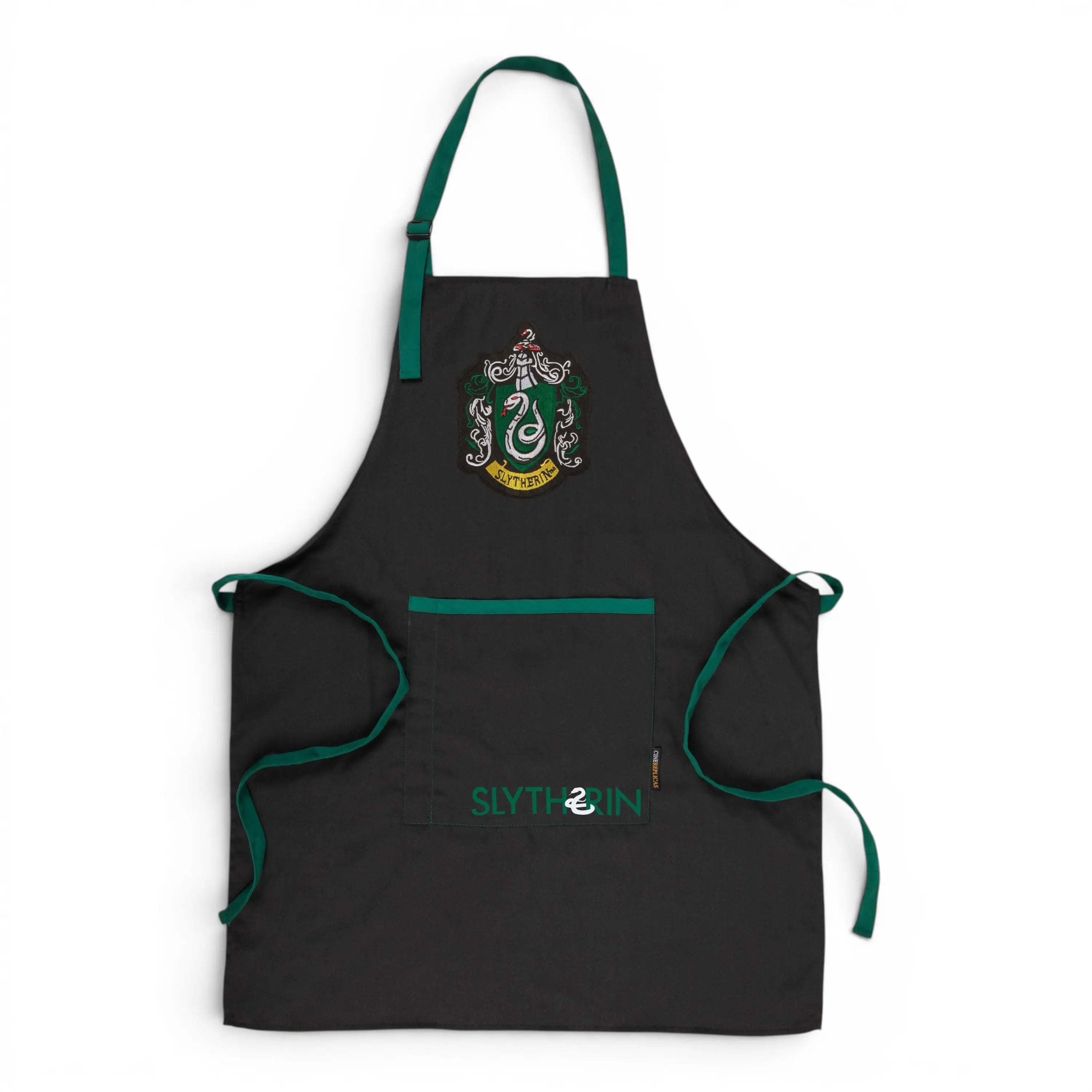 Tablier noir La boutique Aux 2 Balais Serpentard Harry Potter avec écusson et inscription vert, 80% polyester, 20% coton, 70x85cm.