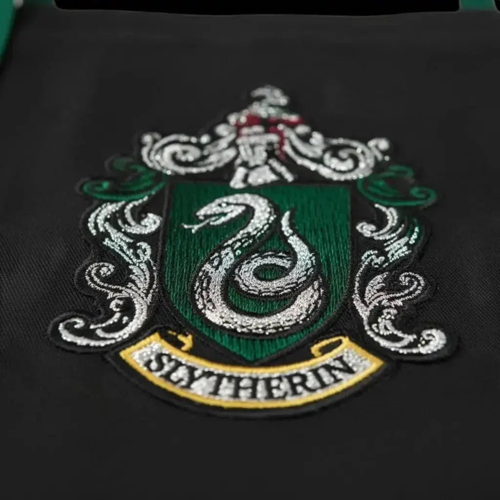 Tablier de cuisine noir La boutique Aux 2 Balais Serpentard Harry Potter avec écusson et inscription SLYTHERIN, 80% polyester 20% coton.
